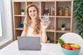 Beautiful blonde woman shopping online with laptop looking positive and happy standing and smiling with a confident smile showing Royalty Free Stock Photo