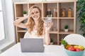 Beautiful blonde woman shopping online with laptop smiling happy doing ok sign with hand on eye looking through fingers Royalty Free Stock Photo