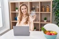 Beautiful blonde woman shopping online with laptop smiling happy pointing with hand and finger Royalty Free Stock Photo