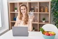 Beautiful blonde woman shopping online with laptop smiling happy and positive, thumb up doing excellent and approval sign Royalty Free Stock Photo