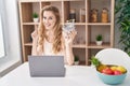 Beautiful blonde woman shopping online with laptop surprised with an idea or question pointing finger with happy face, number one Royalty Free Stock Photo