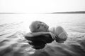 Beautiful blonde woman short hair lies in water on sea shore, pond. Art portrait of a relaxing woman in the water on shore Royalty Free Stock Photo