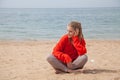 Beautiful blonde woman sits on a sandy beach alone Royalty Free Stock Photo