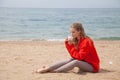 Beautiful blonde woman sits on a sandy beach alone Royalty Free Stock Photo