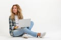 Beautiful blonde woman sitting on floor with laptop on white background Royalty Free Stock Photo