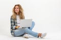 Beautiful blonde woman sitting on floor with laptop on white background Royalty Free Stock Photo