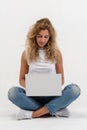 Beautiful blonde woman sitting on floor with laptop on white background Royalty Free Stock Photo