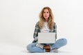 Beautiful blonde woman sitting on floor with laptop on white background Royalty Free Stock Photo