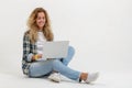 Beautiful blonde woman sitting on floor with laptop on white background Royalty Free Stock Photo