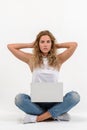 Beautiful blonde woman sitting on floor with laptop on white background Royalty Free Stock Photo