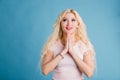 Beautiful blonde woman closes her eyes and pleading for the best on blue background