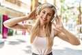 Beautiful blonde woman smiling happy outdoors on a sunny day wearing headphones listening to music Royalty Free Stock Photo