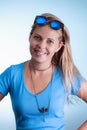 Beautiful blonde woman smiling wearing blue top and sunglasses o