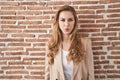 Beautiful blonde woman standing over bricks wall puffing cheeks with funny face Royalty Free Stock Photo