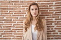 Beautiful blonde woman standing over bricks wall relaxed with serious expression on face Royalty Free Stock Photo