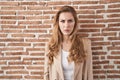 Beautiful blonde woman standing over bricks wall skeptic and nervous, frowning upset because of problem Royalty Free Stock Photo