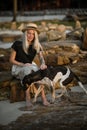 Beautiful blonde woman in straw hat sitting on a rock and petting the good dog. The same color. Thai beach. Morning walk Royalty Free Stock Photo