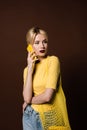 beautiful blonde woman with string bag talking by yellow smartphone and looking away