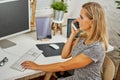Beautiful blonde woman talking on the mobile phone at the desk in the office Royalty Free Stock Photo