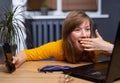 Beautiful blonde woman using laptop and smartphone over home office background with hand on mouth. Sleep mask on table Royalty Free Stock Photo