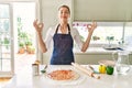 Beautiful blonde woman wearing apron cooking pizza relax and smiling with eyes closed doing meditation gesture with fingers