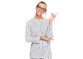 Beautiful blonde woman wearing business shirt and glasses with a big smile on face, pointing with hand and finger to the side Royalty Free Stock Photo