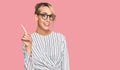 Beautiful blonde woman wearing business shirt and glasses showing and pointing up with finger number one while smiling confident Royalty Free Stock Photo