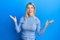 Beautiful blonde woman wearing casual clothes crazy and mad shouting and yelling with aggressive expression and arms raised Royalty Free Stock Photo