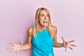 Beautiful blonde woman wearing casual clothes crazy and mad shouting and yelling with aggressive expression and arms raised Royalty Free Stock Photo