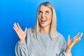 Beautiful blonde woman wearing casual clothes crazy and mad shouting and yelling with aggressive expression and arms raised Royalty Free Stock Photo