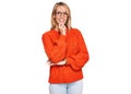 Beautiful blonde woman wearing casual clothes and glasses looking confident at the camera smiling with crossed arms and hand Royalty Free Stock Photo