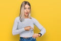 Beautiful blonde woman wearing casual clothes in hurry pointing to watch time, impatience, upset and angry for deadline delay