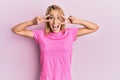 Beautiful blonde woman wearing casual pink tshirt doing peace symbol with fingers over face, smiling cheerful showing victory Royalty Free Stock Photo