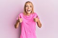 Beautiful blonde woman wearing casual pink tshirt success sign doing positive gesture with hand, thumbs up smiling and happy Royalty Free Stock Photo