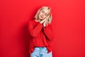 Beautiful blonde woman wearing casual red sweater sleeping tired dreaming and posing with hands together while smiling with closed Royalty Free Stock Photo