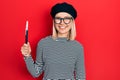 Beautiful blonde woman wearing french look with beret holding painter brushes looking positive and happy standing and smiling with Royalty Free Stock Photo