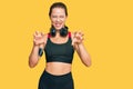 Beautiful blonde woman wearing gym clothes and using headphones smiling funny doing claw gesture as cat, aggressive and sexy Royalty Free Stock Photo