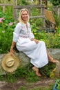 Beautiful blonde woman in white dress sitting outside in garden Royalty Free Stock Photo