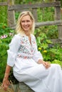 Beautiful blonde woman in white dress sitting outside in garden Royalty Free Stock Photo