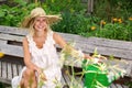 Beautiful blonde woman in white dress sitting outside in garden and smiles Royalty Free Stock Photo