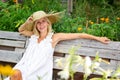 Beautiful blonde woman in white dress sitting outside in garden and smiles Royalty Free Stock Photo