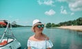 Beautiful blonde woman in white hat and lace sundress with sunglasses. The glasses reflect the beach with umbrella.