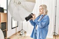 Beautiful blonde woman working as professional photographer at photography studio Royalty Free Stock Photo