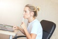 Beautiful blonde woman working on laptop at home. She is thoughtful and focused on work. Freelance, work at home concept. Royalty Free Stock Photo