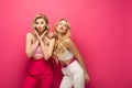 Blonde women blowing air kiss on pink background