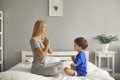 Woman and her son are smiling while sitting in the lotus position on the bed and meditating at home. Royalty Free Stock Photo