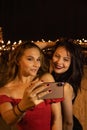 Two pretty girls taking a selfie with a smartphone on a festive night. Royalty Free Stock Photo