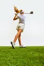 Beautiful, blonde, young girl playing golf on grass, teeing off isolated over white background. Bottom view Royalty Free Stock Photo