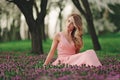 Beautiful blonde young woman in colorful flowers. girl with make-up and hairstyle in pink dress in blossoming spring park. Art Royalty Free Stock Photo