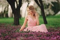 Beautiful blonde young woman in colorful flowers. girl with make-up and hairstyle in pink dress in blossoming spring park. Art Royalty Free Stock Photo